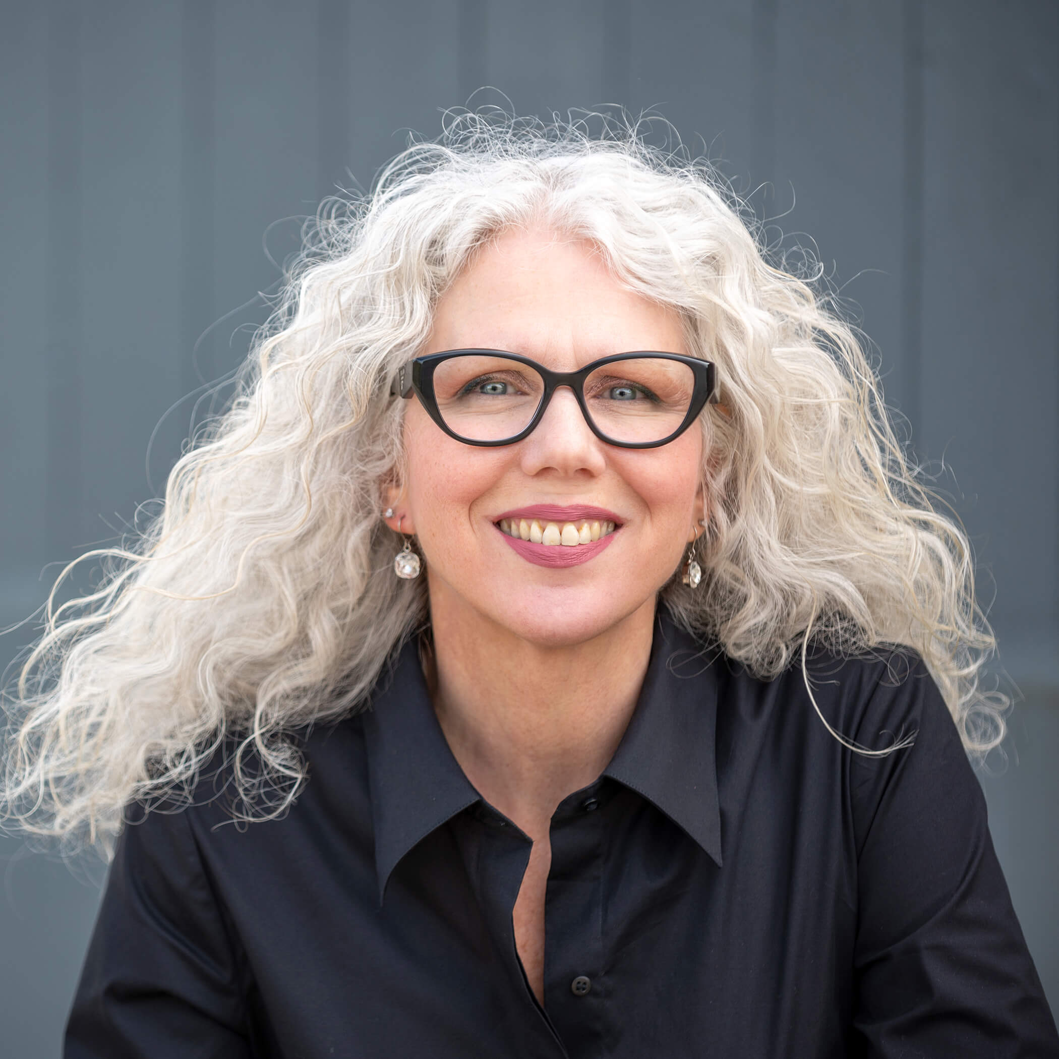 Kate Usher smiling wearing black glasses and black shirt